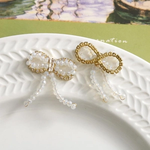 Detail of sweet crystal bowknot earrings with white beads and elegant tassel charms