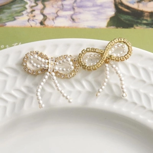 Detailed view of elegant bow jewelry charms with pearls and rhinestones on a ceramic dish