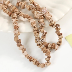 Macro detail of natural irregular marble beads on a white ceramic plate for DIY jewelry