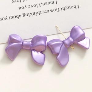Vue macro de breloques nœuds en acrylique violet nacré avec clous et attaches
