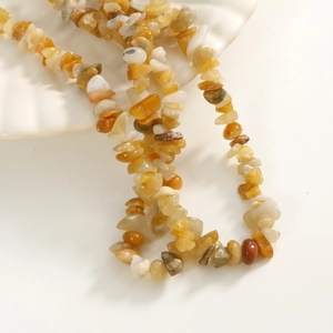 Macro shot of polished natural stone beads in various irregular shapes on a white shell tray