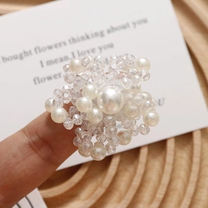 Dettaglio di un anello a fiore con perle sintetiche bianche e perline di cristallo
