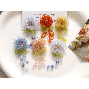 Gros plan de boucles d'oreilles fleurs en perles faites main avec pompons en cristal