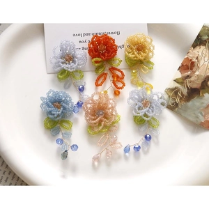 Détails macro de boucles d'oreilles fleurs en perles bleues, orange et roses