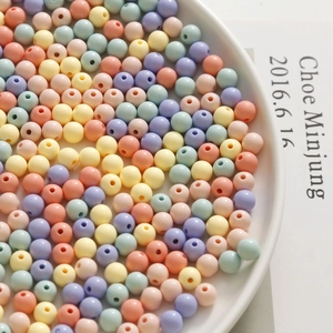 Detailed macro of 8mm pastel macaron acrylic beads for DIY jewelry in a ceramic dish