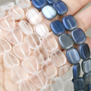 Gedetailleerd zicht op mat matglazen hart- en vierkante kralen in de hand voor DIY-sieraden