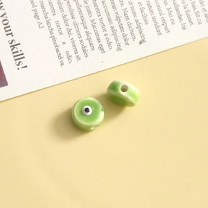 Dettaglio macro di perline a occhio in ceramica verde con foro centrale per gioielli DIY