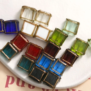 Macro shot of colorful square glass beads with gold glitter edges for DIY jewelry