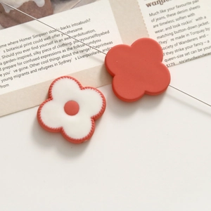 Macro shot of pink acrylic flower charms for DIY jewelry making on a magazine backdrop