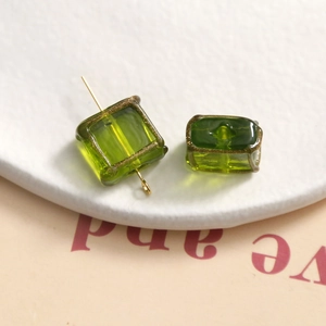 Macro detail of green square glass bead with gold trim and metal pin for jewelry making