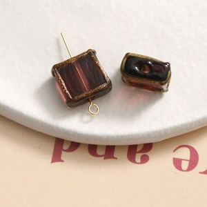 Macro shot of purple glass beads with gold painted edges for DIY jewelry making