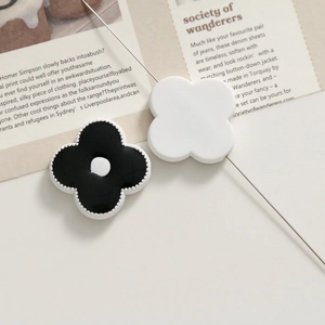 Detail of minimalist black and white floral acrylic charms on an editorial background