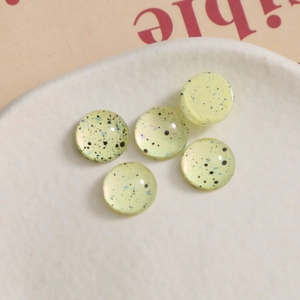 Macro shot of 10mm yellow splatter ink glass cabochons for DIY nail art and jewelry