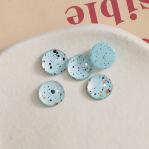 Detail of 10mm light blue ink-splattered glass cabochons for DIY crafts making