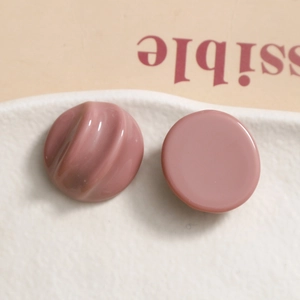 Detail view of pink resin charms with smooth and textured ripples on white stone