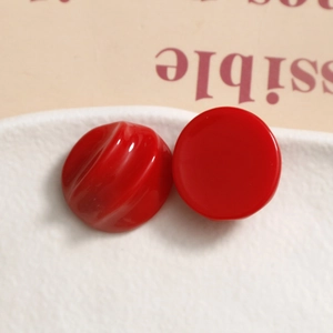Macro detail of red resin semi-circle earrings with smooth and spiral texture surfaces