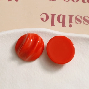 Macro shot of bright red resin round charms with wavy texture and smooth mirror finish