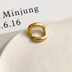 Detail of a matte gold irregular square ring with a minimalist brushed metal finish