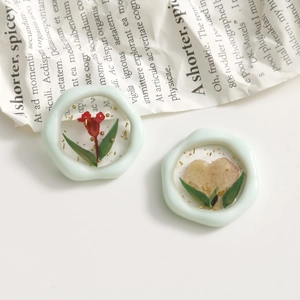 Makroaufnahme von Harzringen in Mint mit echten roten Blumen und Goldfolie