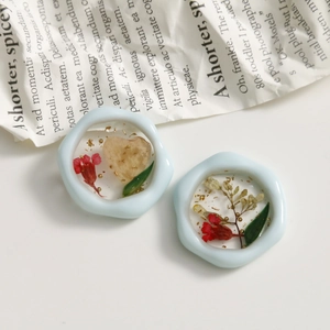 Nahaufnahme von blauem Harzrahmen mit getrockneten roten Blumen und Goldfolie