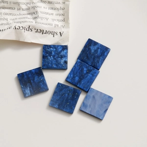 Détail de breloques carrées en résine marbrée bleue avec paillettes dorées pour bijoux