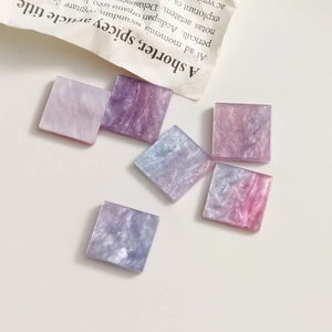 Vue rapprochée de breloques carrées en résine pailletée avec motif marbré violet