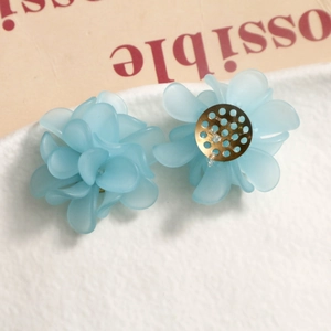 Macro detail of light blue matte resin flower earrings with gold metal base studs