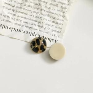 Close-up of leopard print and cream resin round charms on vintage newspaper background