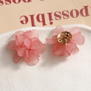 Close-up of matte pink frosted flower earrings with golden metal base on a white tray