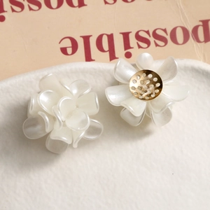 Detail of matte white flower resin earrings with layered petals and gold metal base