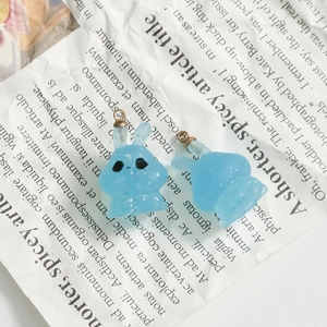 Close-up of translucent light blue resin bunny pendants with silver glitter and gold loops