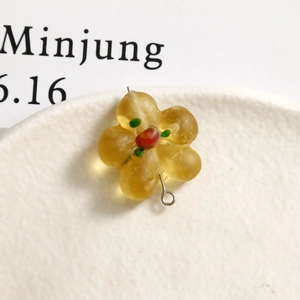 Close-up of yellow frosted flower glass bead with metal pin for DIY jewelry making