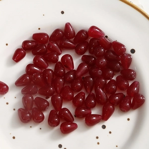 Macro detail of glossy red teardrop beads with holes for DIY jewelry making