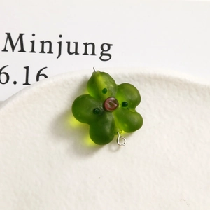 Macro shot of a matte green glass flower bead with silver jump ring for DIY jewelry making
