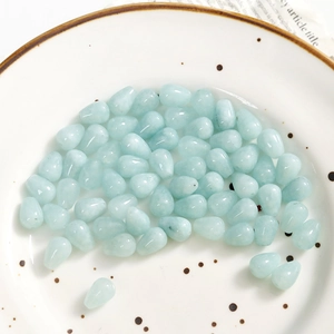 Macro shot of light blue translucent teardrop stones with holes for DIY jewelry