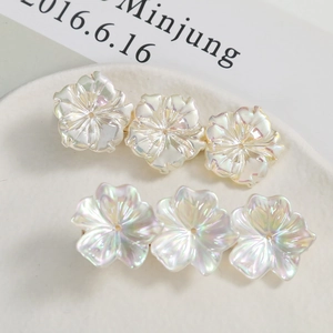 Iridescent flower petal hair clips with pearlescent finish on a white textured plate