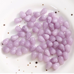 Macro shot of lavender teardrop stone beads with smoky texture on a ceramic plate