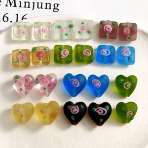 Macro shot of matte heart and square glass beads with hand-painted floral rose patterns