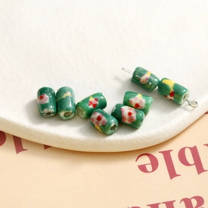 Detailed view of dark green cylindrical ceramic beads with hand-painted floral patterns