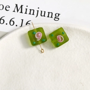 Macro detail of frosted glass square beads with pink rose patterns and gold pins
