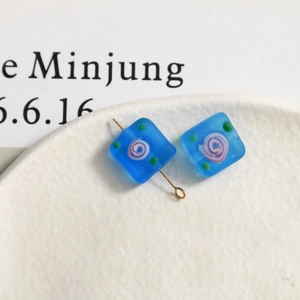 Macro shot of square blue frosted glass beads with floral spiral for DIY jewelry making