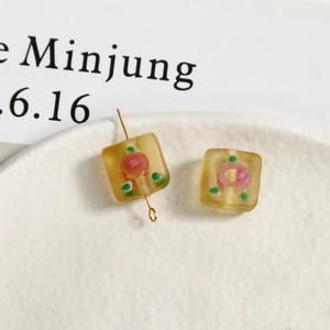 Detail of frosted square glass beads with pink rose pattern and golden metal pin
