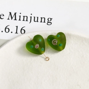 Macro detail of heart-shaped frosted green glass beads with pink spiral for DIY jewelry