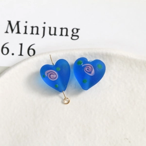 Detail of frosted heart-shaped glass beads with pink spiral and gold metal pins for DIY