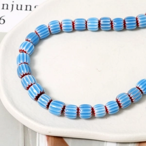 Dettaglio di perle a zucca in ceramica a righe blu e bianche con bordi rossi seghettati