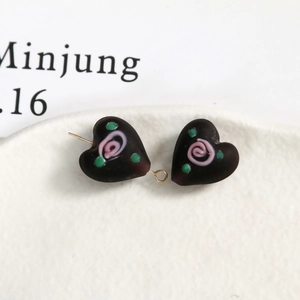 Detail of dark brown heart-shaped glass beads with pink spiral and green dot patterns