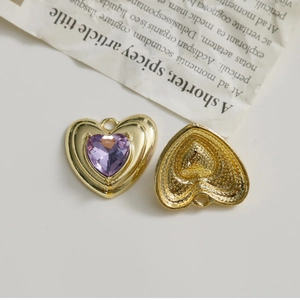 Vue macro de pendentifs cœur dorés avec pierres violettes et dos en métal texturé