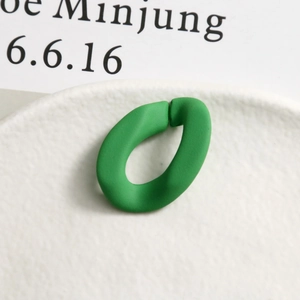 Vue détaillée de boucles d'oreilles ovales en résine mate verte sur une assiette blanche