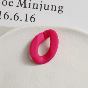 Gros plan d'un accessoire ovale fuchsia mat pour bijoux DIY sur un plateau blanc