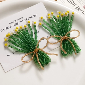 Artistic handmade glass beaded floral hair clips with champagne bow details in a white dish